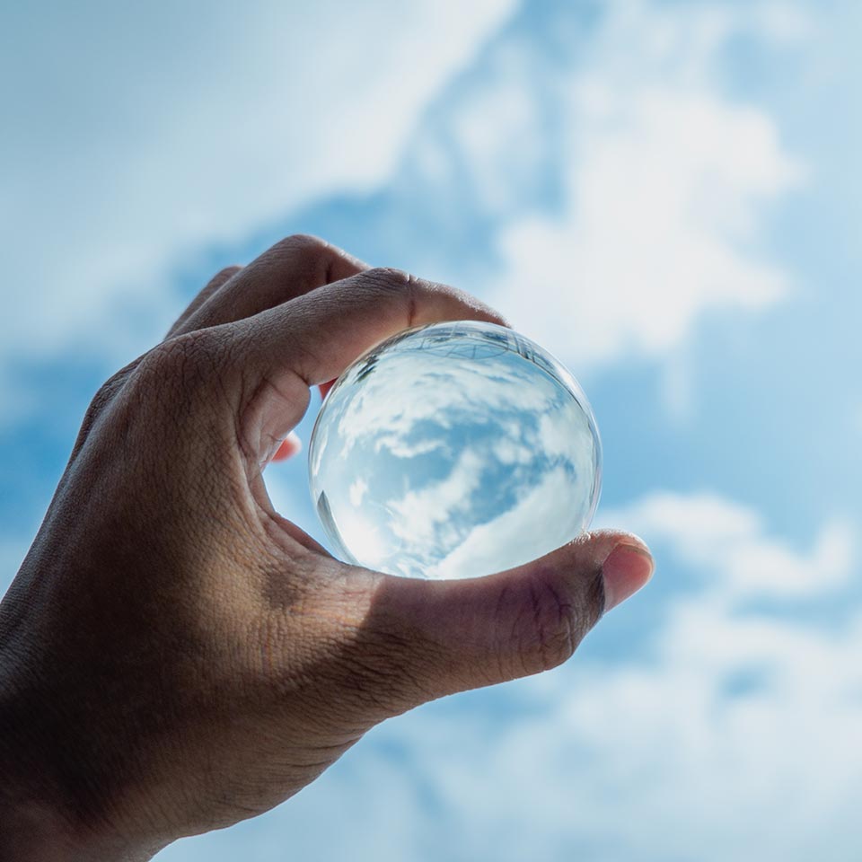 Man holdinga a glassball in the cloudy sky